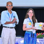 Na zdjęciu są 4 osoby. Jedna z nich, kobieta, odbiera dyplom