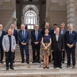 Na zdjęciu grupa osób na schodach w Dużej Auli Gmachu Głównego - przedstawiciele CERN-u i Politechniki Warszawskiej