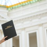 Na zdjęciu widać trzymaną pracę magisterską na tle wnętrza Gmachu Głównego PW